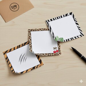 May include: Three square notepads with animal print borders: tiger stripes, leopard spots, and zebra stripes. One notepad has claw marks, another has cherries, and the third has leaves. A pen and a brown envelope are also visible.