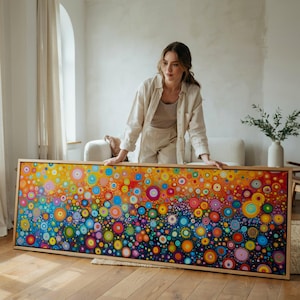Peut inclure: Une grande peinture sur toile rectangulaire présentant une composition dense et vibrante de cercles multicolores dans des tons de jaune, orange, rouge, rose, bleu et vert. L'œuvre est encadrée en bois clair et affiche un dégradé de tons chauds.