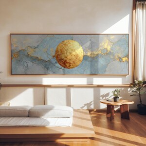 Peut inclure: Une grande œuvre d'art murale rectangulaire avec une sphère dorée sur un fond de motifs abstraits bleus et dorés. L'œuvre est encadrée dans un cadre en bois brun clair, ajoutant une touche de chaleur au design.