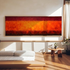 May include: A large rectangular abstract painting with a wooden frame. The artwork features horizontal bands of color, transitioning from deep red at the top to vibrant orange and yellow in the center, and a dark red at the bottom. The painting is displayed in a well-lit room.
