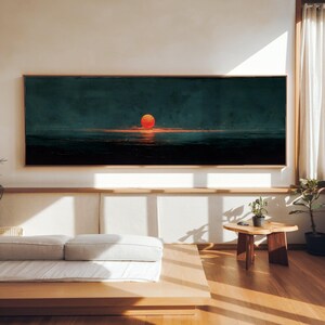Peut inclure: Une œuvre d'art murale rectangulaire panoramique représentant un paysage nocturne bleu sarcelle foncé et noir avec un soleil orange vif centré à l'horizon, reflétant la lumière sur l'eau sombre, encadrée d'une fine bordure en bois clair.