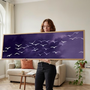 Peut inclure: Une œuvre d'art murale rectangulaire panoramique représentant un ciel violet profond rempli d'une volée d'oiseaux blancs en plein vol. L'œuvre est encadrée dans un cadre en bois clair, soulignant le contraste entre le fond sombre et les oiseaux.