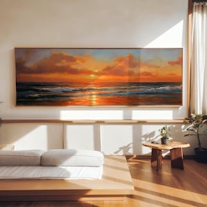 Peut inclure: Peinture encadrée d'un paysage marin au coucher du soleil. L'œuvre présente un ciel aux couleurs chaudes, allant de l'orange au rouge et au jaune, se reflétant sur l'eau. Les vagues sont visibles. Le tableau est exposé dans une pièce bien éclairée.