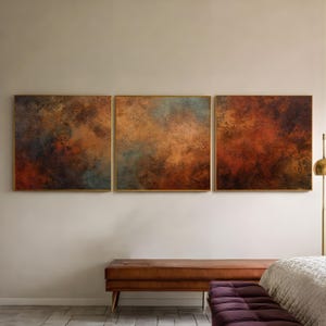 Può includere: Tre dipinti astratti incorniciati con una tavolozza di colori terrosi strutturati di marroni, arancioni e blu. L'opera d'arte è esposta sopra una panca marrone con un cuscino viola, creando un'atmosfera calda e invitante.