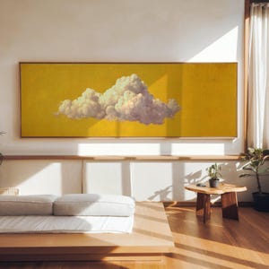 May include: A rectangular canvas artwork depicting a cloud against a yellow backdrop, framed in natural wood. The cloud is white and fluffy. The artwork hangs above a low wooden platform, part of a minimalist interior design scheme.