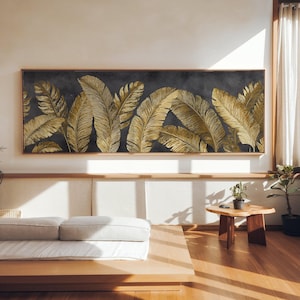 Peut inclure: Une grande œuvre d'art rectangulaire avec un fond gris foncé et des motifs de plumes dorées stylisées. L'œuvre est encadrée dans un cadre en bois brun clair. L'œuvre est affichée au-dessus d'une plateforme en bois, ajoutant une touche de chaleur.