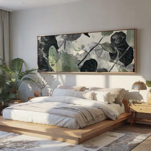 Könnte beinhalten: Schlafzimmer mit einem großen, rechteckigen Leinwandbild mit einem botanischen Druck in Grün-, Grau- und Schwarztönen. Das Kunstwerk hängt über einem Bett mit hellfarbener Bettwäsche. Ein Nachttisch aus Holz und eine Topfpflanze sind ebenfalls zu sehen.