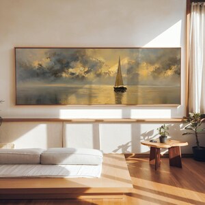 Peut inclure: Peinture encadrée représentant un voilier sur l'eau sous un ciel nuageux. L'œuvre utilise une palette de couleurs chaudes avec des tons dorés et gris, créant une scène paisible. Le tableau est exposé dans un intérieur moderne et lumineux.