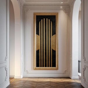 Könnte beinhalten: Gerahmtes abstraktes Kunstwerk mit goldenem Rahmen. Das Kunstwerk zeigt vertikale goldene Streifen auf schwarzem Hintergrund, mit goldenen Halbkreisen auf beiden Seiten. Es hängt in einem Flur mit weißen Wänden und Holzboden.
