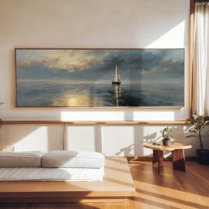 Puede incluir: Pintura enmarcada de un velero en el mar bajo un cielo nublado. La obra de arte se exhibe en una habitación con un diseño moderno. La paleta de colores incluye azules, blancos y dorados. El marco es de madera. La pintura es rectangular.