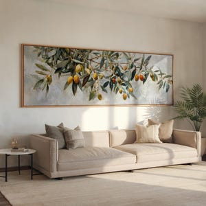 Peut inclure: Une grande peinture rectangulaire encadrée représente une branche d'olivier avec des feuilles vertes et des olives jaunes et rouges. La peinture est accrochée au-dessus d'un canapé sectionnel beige avec plusieurs coussins. Une petite table d'appoint et une plante en pot sont également dans la pièce.
