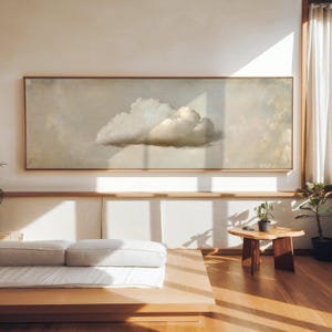 Peut inclure: Une grande œuvre d'art rectangulaire encadrée représentant une formation nuageuse dans des tons de blanc, de gris et de beige. L'œuvre est accrochée sur un mur clair au-dessus d'une plateforme en bois avec un matelas. La pièce a un design minimaliste.