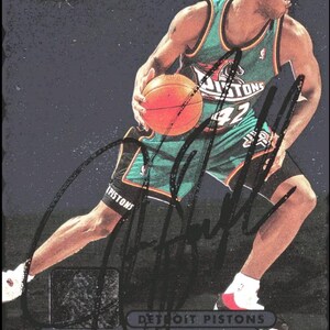 May include: A basketball trading card featuring Jerry Stackhouse of the Detroit Pistons. The card shows Stackhouse in his Pistons uniform, holding a basketball. The card has a dark background with the words "Metal Universe" at the top.