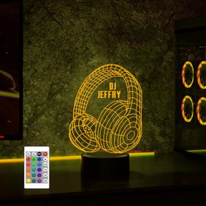 May include: A yellow 3D printed night light shaped like headphones with the text "DJ JEFFRY" on the side. The light is on a black base and has a remote control with multiple color options.