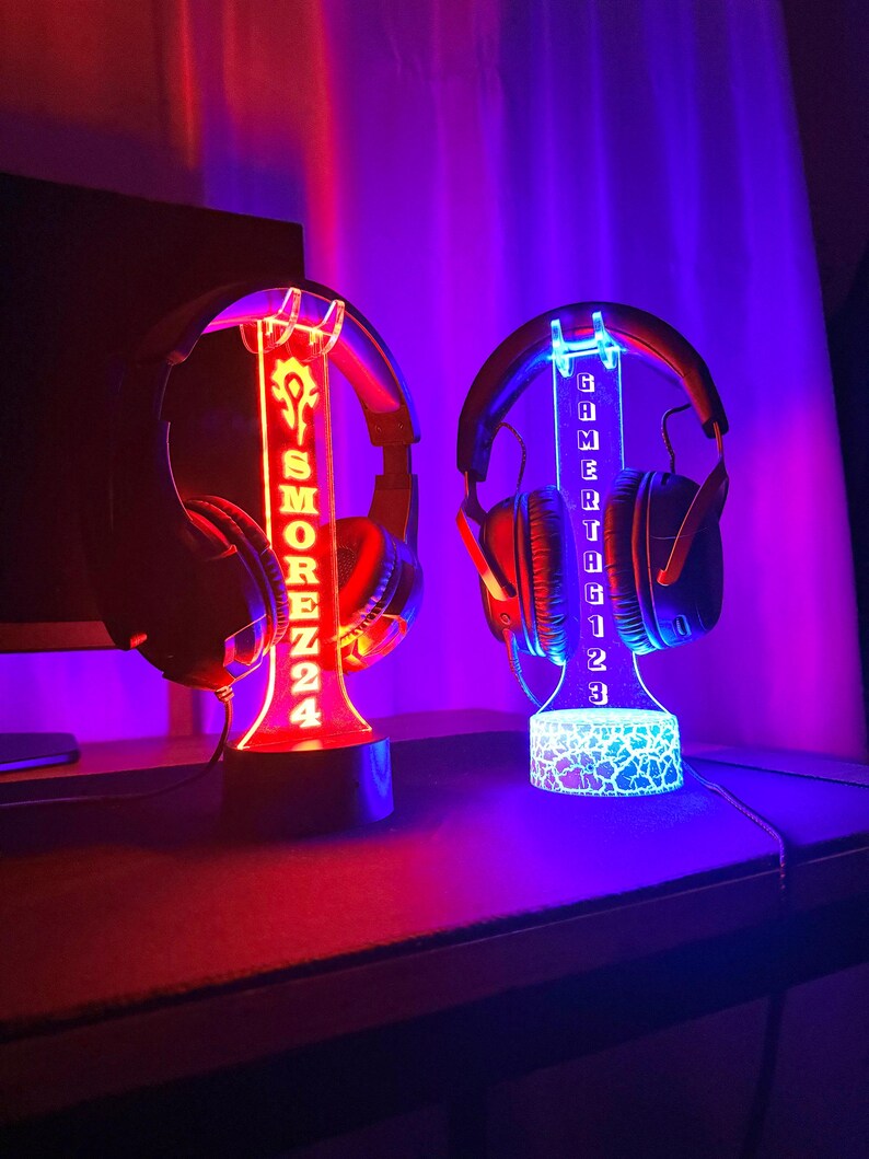May include: Two illuminated headphone stands with custom engraved names. The stand on the left is red and says "SMOREZZ24". The stand on the right is blue and says "GAMERTHG123".