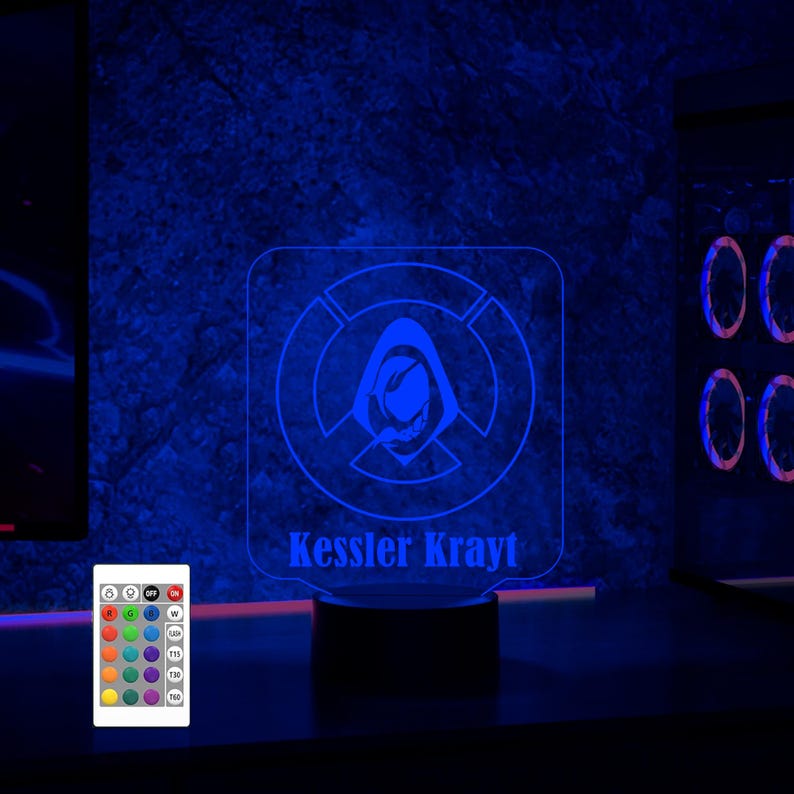 May include: A blue LED night light with a white silhouette of a hooded figure and a circle with a cross inside. The light has a base with the text "Kessler Krayt" and a remote control with color options.