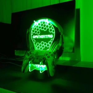 May include: Green LED light with a honeycomb design and the word "GAMERTAG" in the center. The light is mounted on a stand that holds a video game controller and headphones.