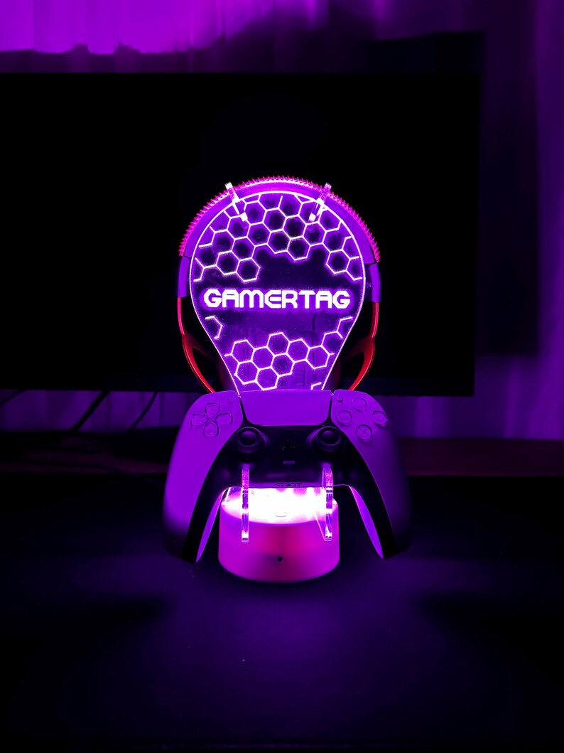 May include: A purple and white LED light with a honeycomb design and the word "GAMERTAG" in white. The light is mounted on a black controller.