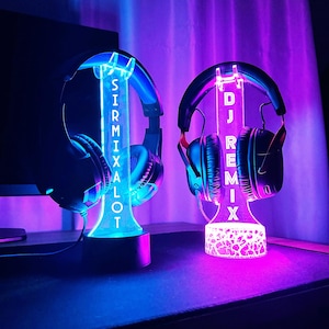 Peut inclure: Deux supports de casque lumineux, l'un avec le texte "SIRMIXALOT", l'autre "DJ REMIX". Chacun supporte un casque. Les supports sont &eacute;clair&eacute;s par des LED bleues et violettes, cr&eacute;ant un affichage vibrant et color&eacute;.