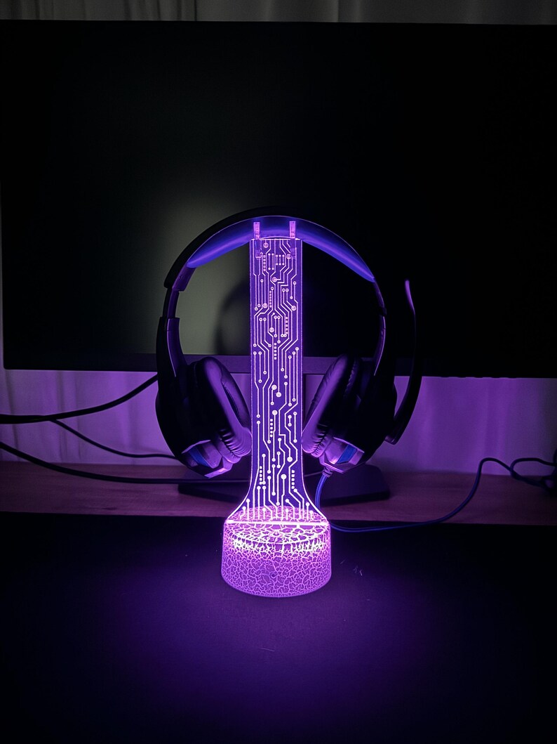 Puede incluir: Una luz LED p&uacute;rpura con un dise&ntilde;o de placa de circuito y una base texturizada. La luz est&aacute; dise&ntilde;ada para sostener auriculares.