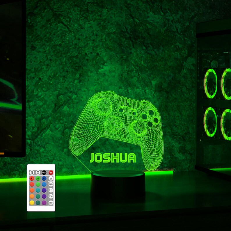 May include: A green 3D printed night light shaped like a video game controller with the name "Joshua" printed below it. The night light is on a black base and has a remote control with multiple color options.