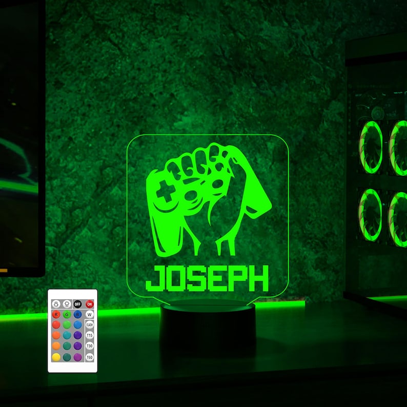 May include: Green LED night light with a gamer hand holding a controller and the name "JOSEPH" below. The light is on a black base and comes with a remote control.