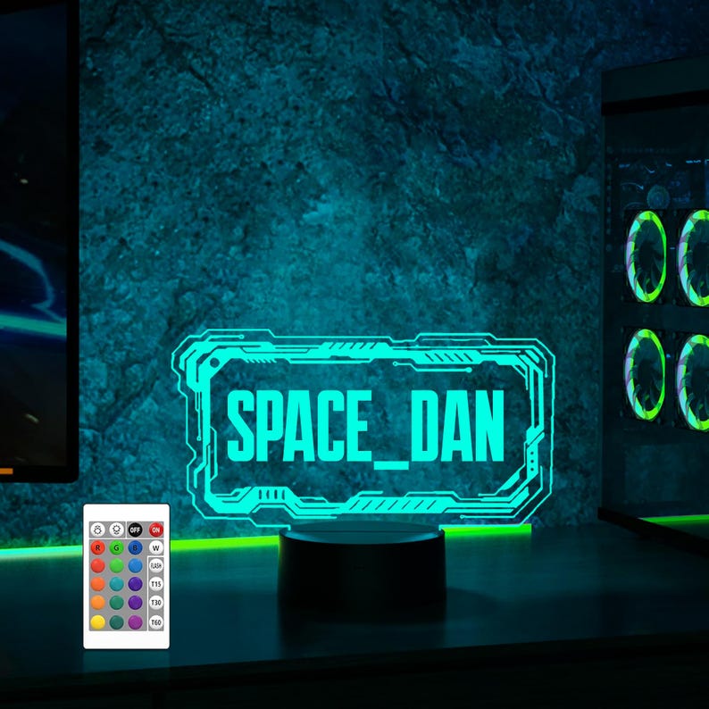 May include: A blue and green neon sign with the text "SPACE_DAN" in a futuristic font. The sign is on a black base and is illuminated with a variety of colors.