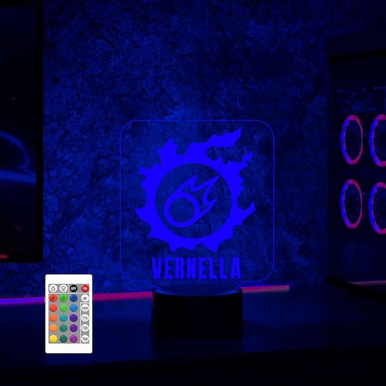 May include: A blue and white LED night light with a fire symbol and the name "VERNELLA" printed below. The light is on a black base and comes with a remote control.