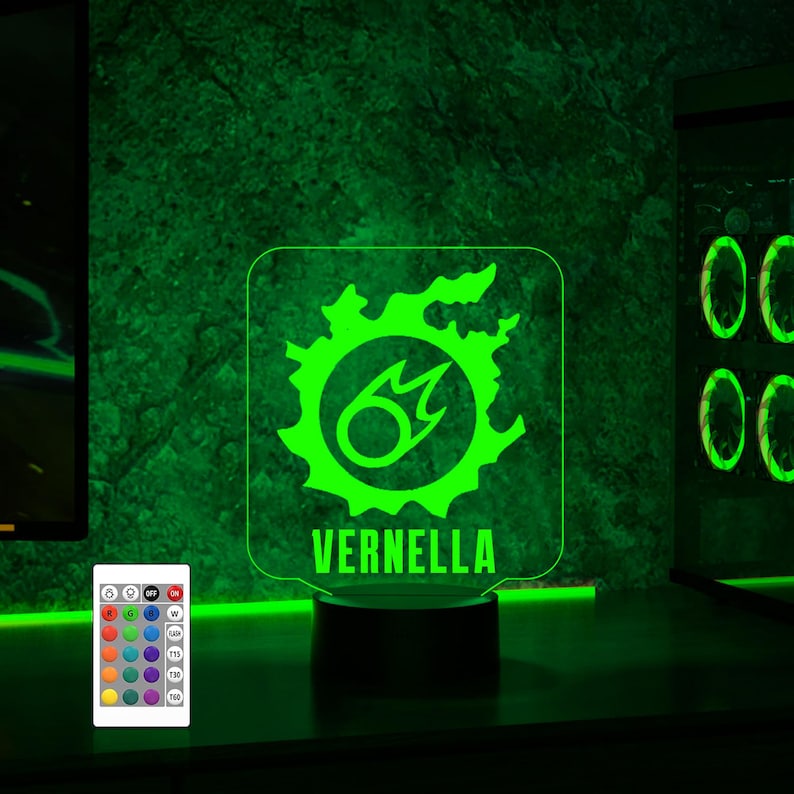 May include: A green and white LED night light with a stylised flame design and the name "VERNELLA" printed below. The light is on a black base and has a remote control with multiple colour options.