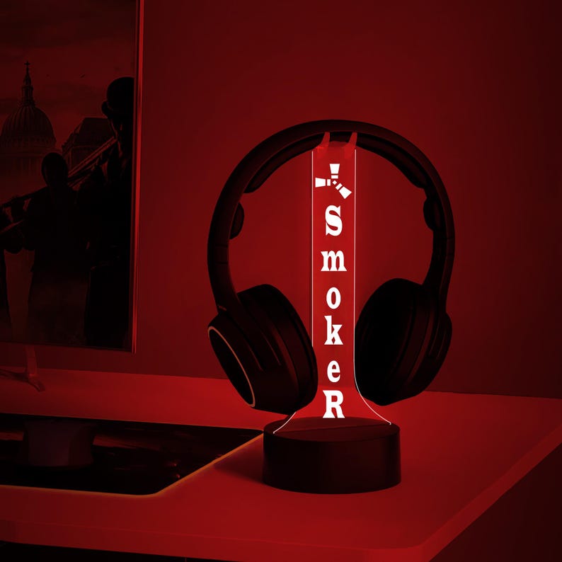 May include: A black and red 3D printed lamp with the word "SMOKER" printed on it. The lamp is shaped like a tall, thin cylinder and has a black headphone on top of it.