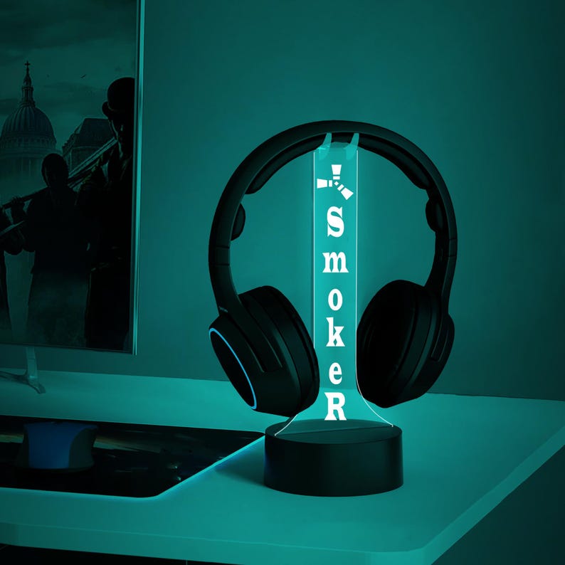 May include: A black and blue illuminated headphone stand with the word "SMOKER" printed on it. The stand is lit up with a blue light and has a black base.