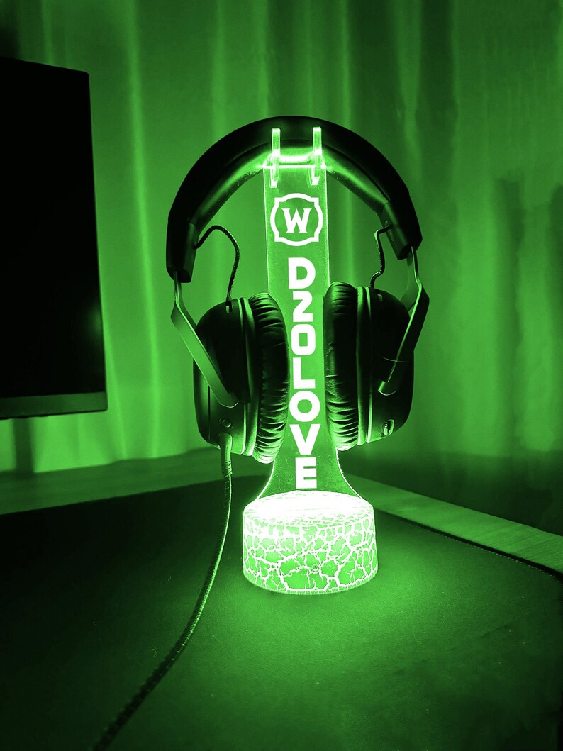 Op de afbeelding: Een groene LED-lichtstandaard met een transparant acryl paneel waarop "W D2OLOVE" staat en die een zwarte koptelefoon vasthoudt.