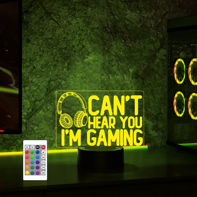 May include: A yellow LED night light with a gamer-themed design. The light features a pair of headphones and the text "Can't hear you I'm gaming".