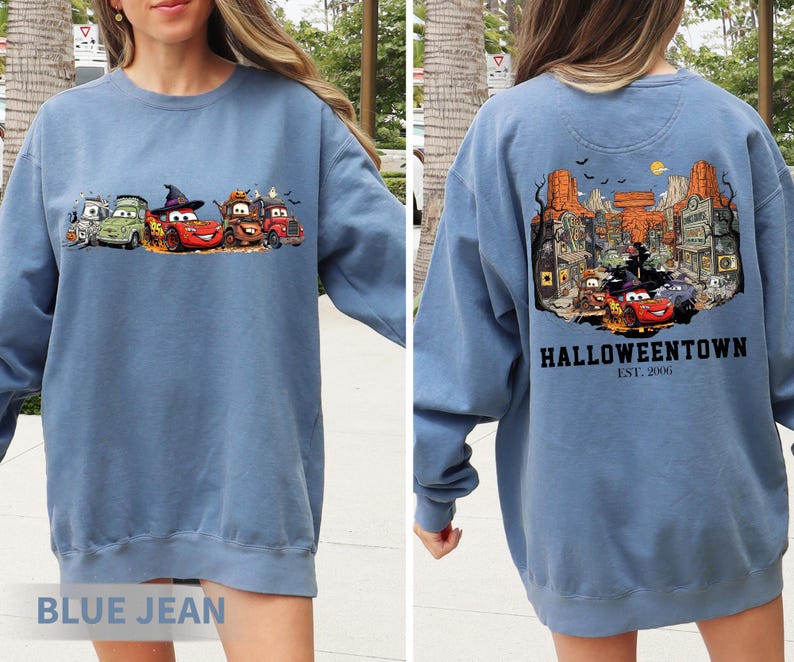 K&ouml;nnte beinhalten: Blaues Jeans-Sweatshirt mit Halloween-Motiv. Auf der Vorderseite sind Cartoon-Autos in Kost&uuml;men abgebildet, auf der R&uuml;ckseite eine Stadtszene mit "Halloweentown Est. 2006". Ein bequemes Langarm-Oberteil f&uuml;r die gruselige Jahreszeit.