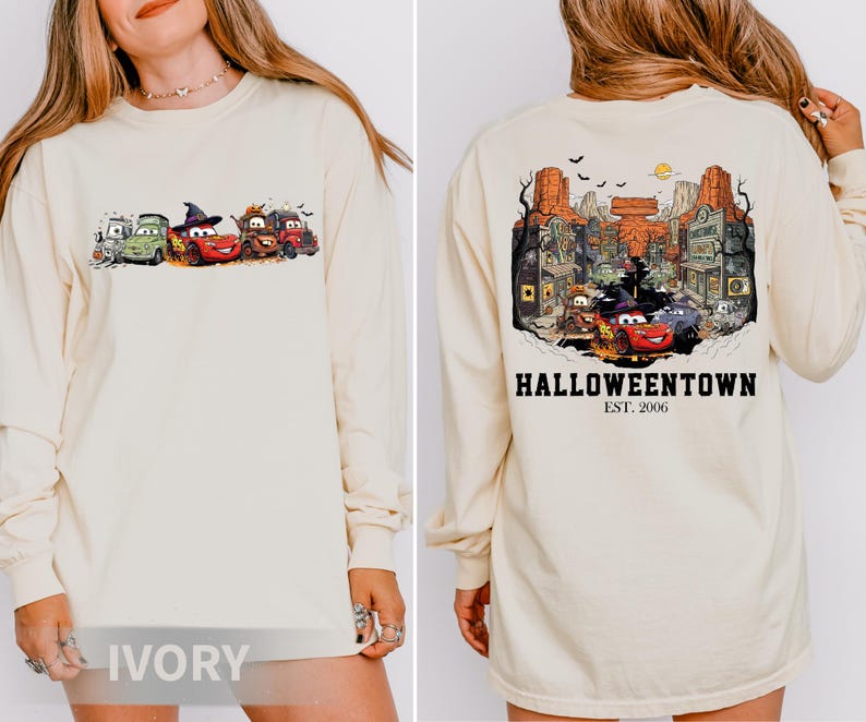 K&ouml;nnte beinhalten: Elfenbeinfarbenes Langarmshirt mit einem Halloween-Motiv von Zeichentrickautos auf der Vorderseite. Auf der R&uuml;ckseite des Shirts befindet sich eine detaillierte Illustration einer Stadt mit dem Text "Halloweentown Est. 2006".