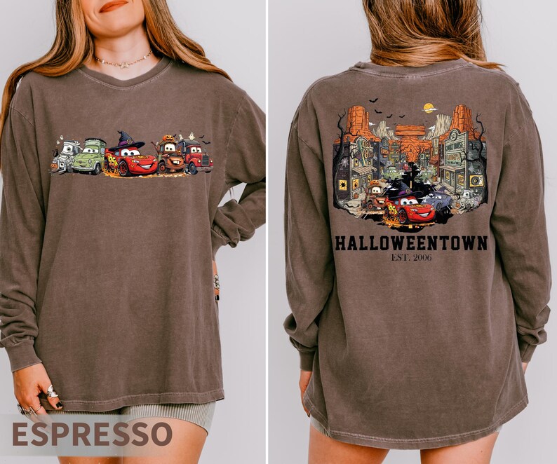 K&ouml;nnte beinhalten: Lang&auml;rmliges Espresso-farbenes T-Shirt mit einem Cartoon-Auto-Motiv auf der Vorderseite und einer detaillierten Illustration einer Stadt mit dem Text "Halloweentown Est. 2006" auf der R&uuml;ckseite. Das Shirt hat eine lockere Passform.