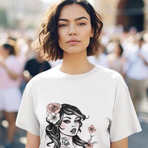 Puede incluir: Camiseta blanca con una ilustración en blanco y negro de una mujer con flores rosas en el pelo. El texto "I'd so don't like this" está impreso debajo de la ilustración.