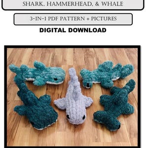 May include: A collection of handmade crochet shark, hammerhead, and whale plushies in shades of blue and gray, arranged on a wooden surface. The text "SHARK FRIENDS" and "DIGITAL DOWNLOAD" are visible.
