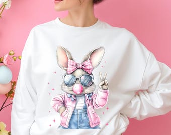 May include: White sweatshirt with a graphic of a cartoon bunny wearing pink sunglasses, a pink bow, and a pink jacket. The bunny is holding a pink bubble.