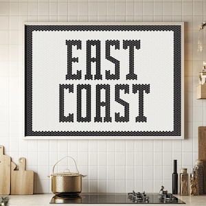 Può includere: Un cartello in mosaico di piastrelle bianche e nere incorniciato con il testo "EAST COAST" in un carattere audace e robusto.