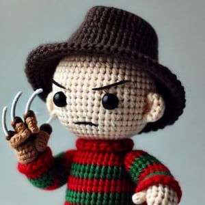 May include: Crocheted doll of a character wearing a brown hat and a red and green striped sweater. The doll has black eyes, a stern expression, and a clawed glove. The doll is handmade.