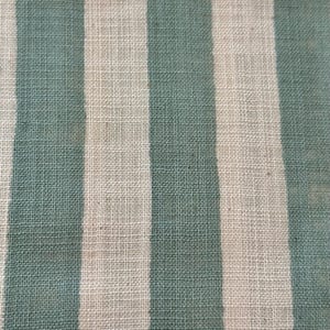 May include: A woven fabric featuring a repeating pattern of vertical stripes in alternating shades of muted sage green and off-white. The textile displays a visible, textured weave with a consistent grid-like structure throughout the entire surface.