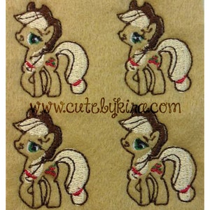 May include: Four embroidered brown and white pony figures with a red berry on their flank. The ponies have brown manes and tails. The background is a light brown fabric.