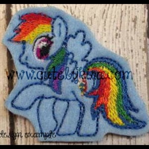 May include: A blue and rainbow embroidered patch of a cartoon pony with a rainbow mane and tail. The pony has a single large eye with a purple iris. The patch is a design example.