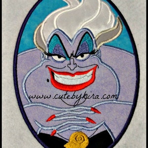 May include: An embroidered patch of Ursula, the sea witch from Disney's The Little Mermaid. She has purple skin, white hair, and a wicked smile. The patch is in an oval shape with a blue background and a black border. The text "www.cutebykira.com" is visible at the bottom of the patch.