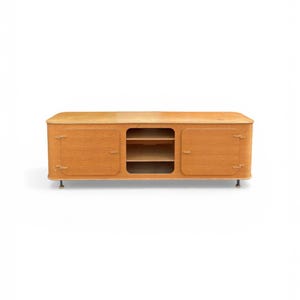 May include: A light-colored wooden cabinet with a rounded top and sides. The cabinet has two doors and an open shelf area in the center. It stands on short, silver-colored legs.