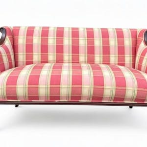 May include: A two-seater sofa featuring a red, cream, and light green plaid fabric upholstery. The frame is constructed from dark brown wood with curved armrests, a carved front rail, and four cabriole legs finished with small metal casters.
