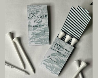 May include: A set of white golf tees and two rectangular paper matchbook-style holders. One holder features a green tree illustration and the text The Fender Club EST. 2026. The other holder displays the text THANKS FOR COMING TO OUR PAR-TEE!