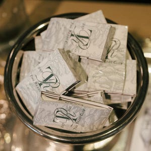 May include: A collection of rectangular matchboxes with a light gray and white botanical pattern. Each box features a dark green monogram logo with the letters TR, the text EST 2025, and the words THE BRADY CLUB printed on the front surface.