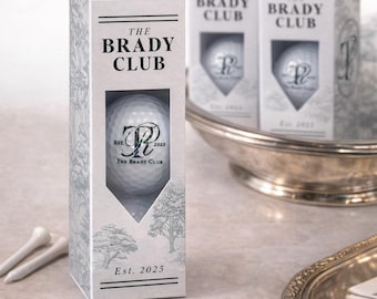 May include: Golf ball gift boxes with the text "THE BRADY CLUB" and "Est. 2025". The boxes are white with a tree design and a window showing a golf ball. The golf balls have a "BR" logo. Text at the bottom says "DIGITAL PROOF SENT BEFORE PRINTING".